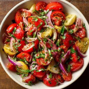 Tuscan tomato salad with heirloom tomatoes, cucumber, red onion, basil, and olives in a rustic bowl