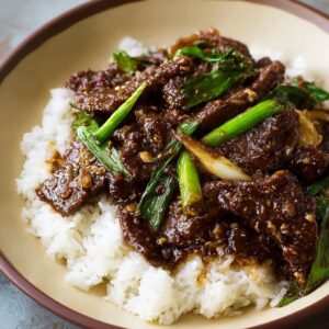 Mongolian beef with glossy sauce served over steamed white rice garnished with green onions