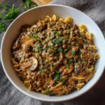 Vegan lentil mushroom stroganoff served over egg-free noodles with fresh parsley and creamy dairy-free sauce
