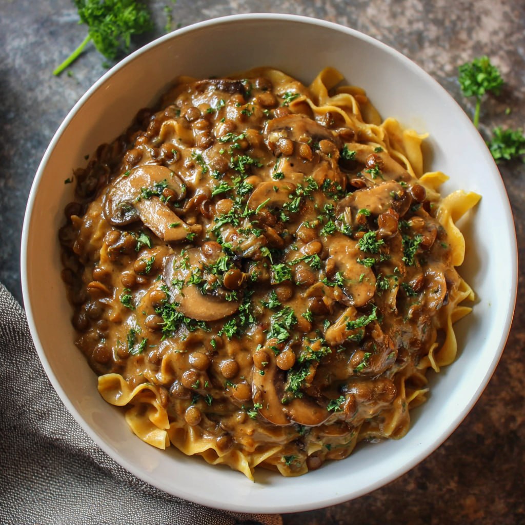 Close-up of creamy vegan stroganoff with lentils mushrooms and rich coconut cream sauce over pasta