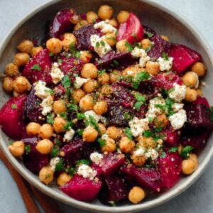 Chickpea beet feta salad in a wooden bowl with vibrant pink-stained chickpeas, crumbled feta, fresh dill, and arugula