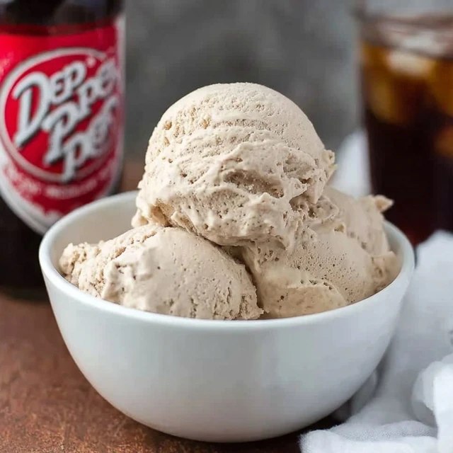 Close-up of Dr Pepper ice cream showing rich caramel-cherry hued scoops, smooth no-churn texture, swirls of reduced syrup, sprinkle of crushed cherry on top