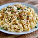 Fettuccine alfredo with parsley in a bowl, ribbons of fettuccine coated in a creamy white parmesan alfredo sauce, sprinkled with chopped parsley and black pepper